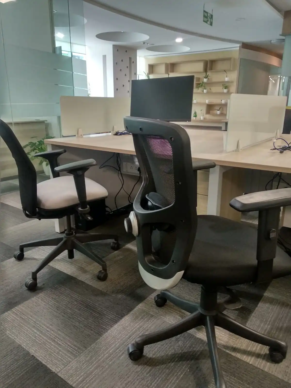 An office workspace with desks, monitors and office chairs